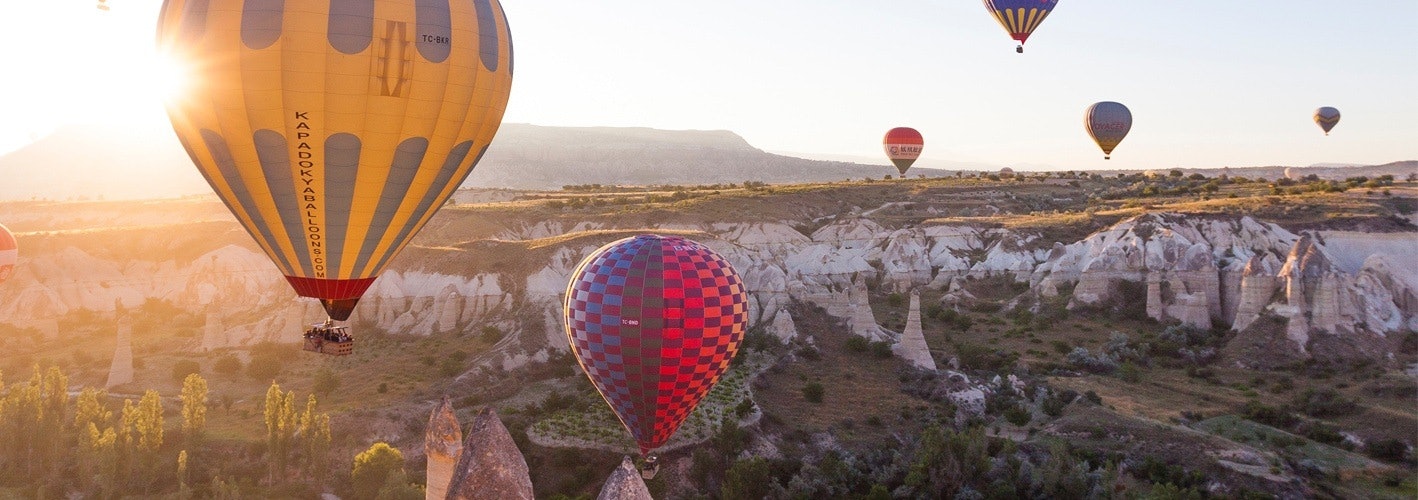 hot air balloons rising over a desert